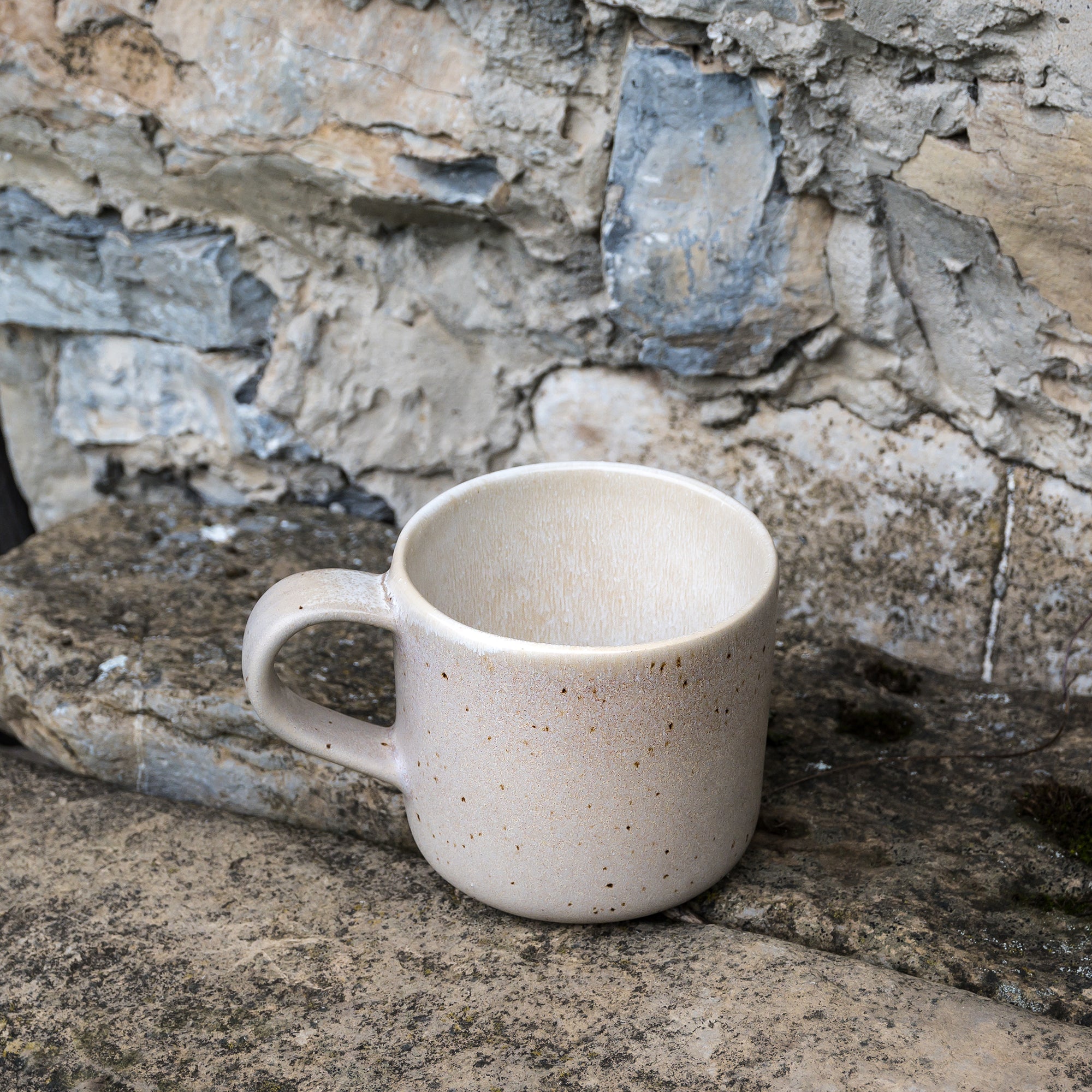 Steingut Tasse in Beige auf Steinboden.